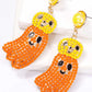 Two Halloween ghost-shaped dangle earrings with yellow and orange beads.