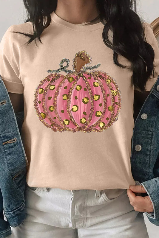A woman wears a beige t-shirt with a pink, glittery, leopard-print pumpkin design.