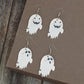Four ghost-shaped dangle earrings, two with smiling faces and two with sad faces.