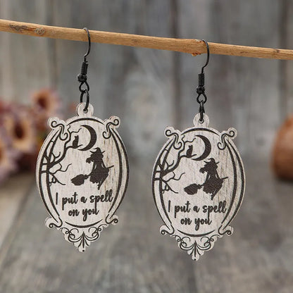 Two wooden dangle earrings feature a witch on a broomstick and the phrase "I put a spell on you."