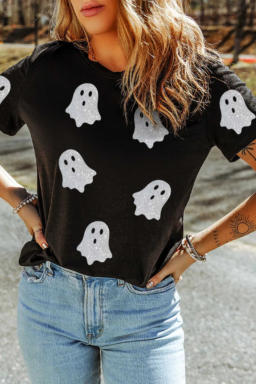 Black short-sleeve t-shirt with glitter ghost print and light wash jeans.