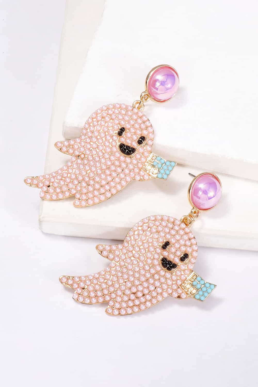 Two ghost-shaped dangle earrings with pink synthetic pearls and black and blue accents.