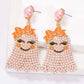 Smiling ghost shape synthetic pearl earrings with orange bows.