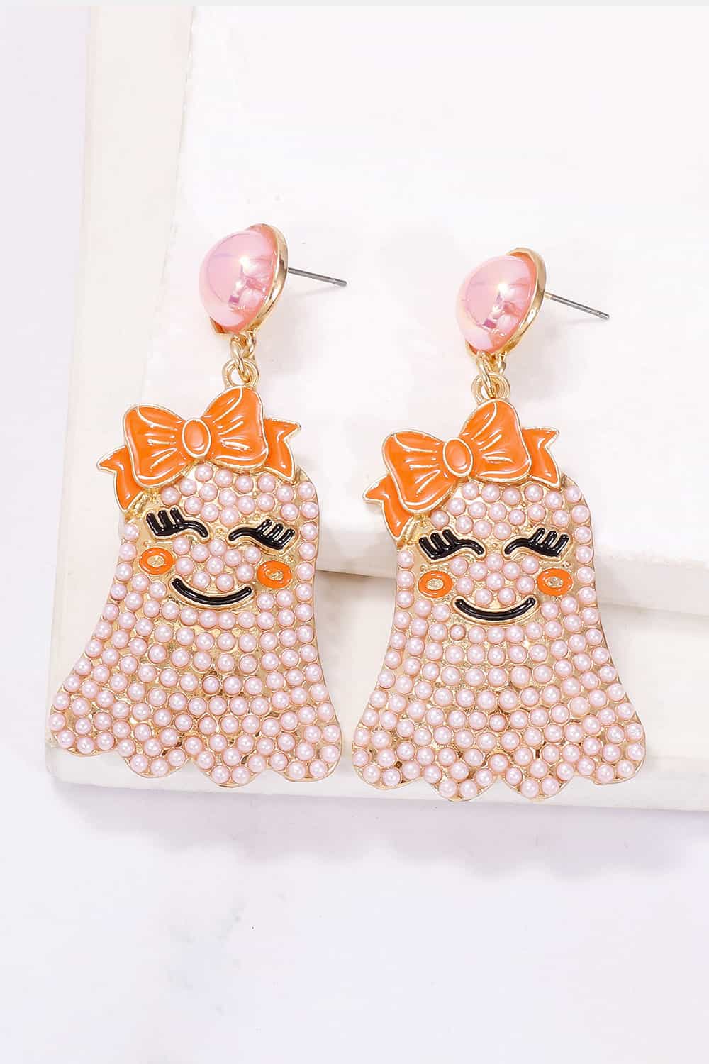 Smiling ghost shape synthetic pearl earrings with orange bows.