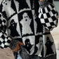 Black and white ghost pattern sweater with checkerboard sleeves.