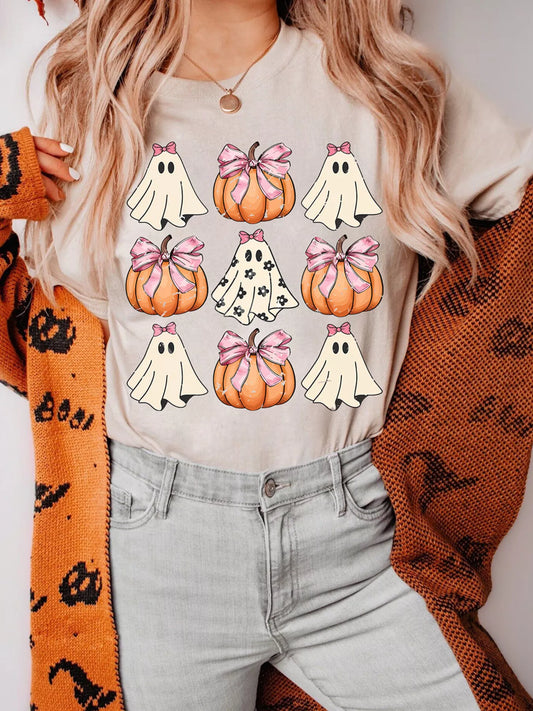 A woman wears a Halloween graphic t-shirt with ghosts and pumpkins, light jeans, and a cardigan.