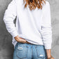 A woman from behind wears a white long-sleeve dropped shoulder sweatshirt and distressed jeans.