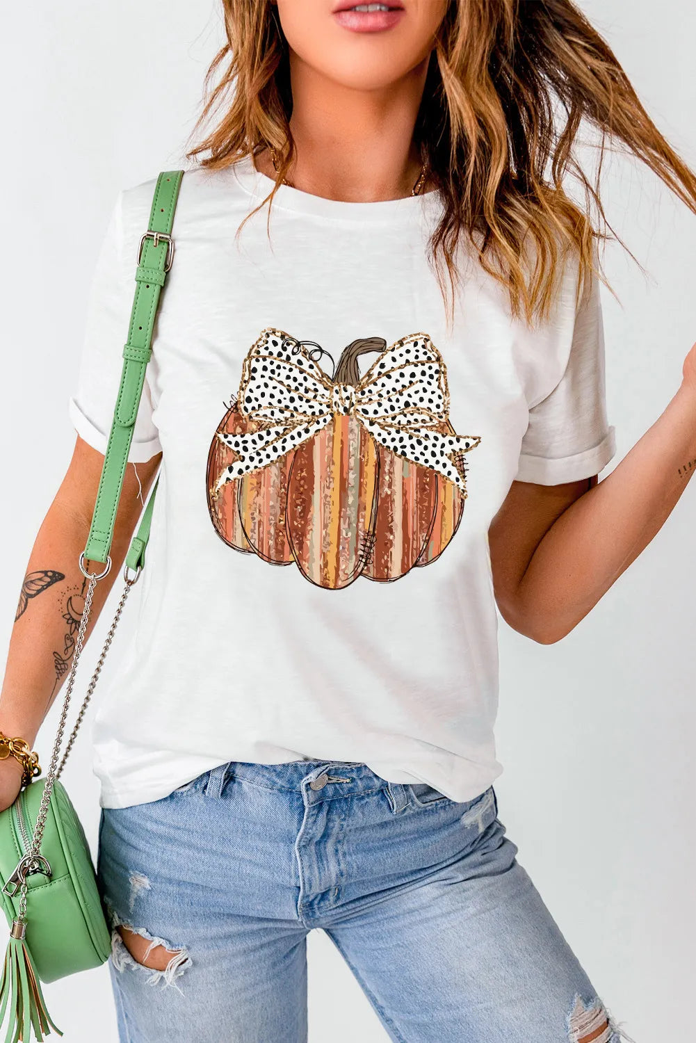 A woman wears a white short-sleeve t-shirt with a pumpkin graphic.