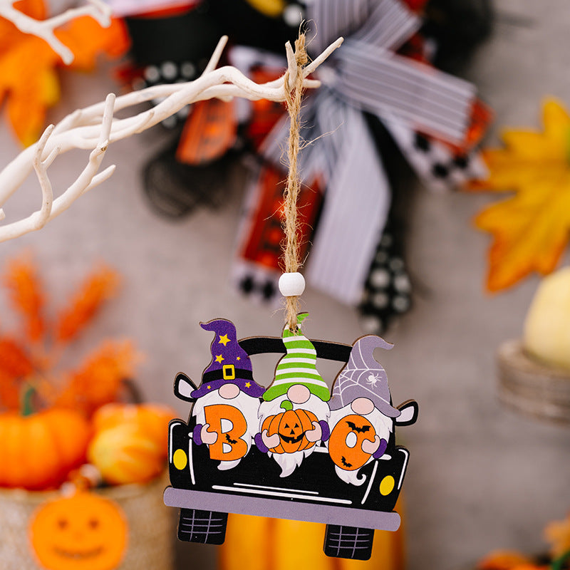Four Halloween gnome ornaments in a car hang from a white branch.