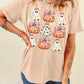 A woman wears a light pink t-shirt with a Halloween ghost and pumpkin graphic.