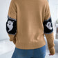 A woman from behind wears a tan long-sleeve sweater with black and white ghost sleeves.