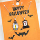 Two Halloween-themed necklaces, one with a lantern and one with a tombstone, on an orange card.