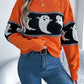 Orange long-sleeve sweater with a black and white ghost pattern.