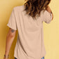 A woman from behind wearing a beige short-sleeve t-shirt and blue jeans.