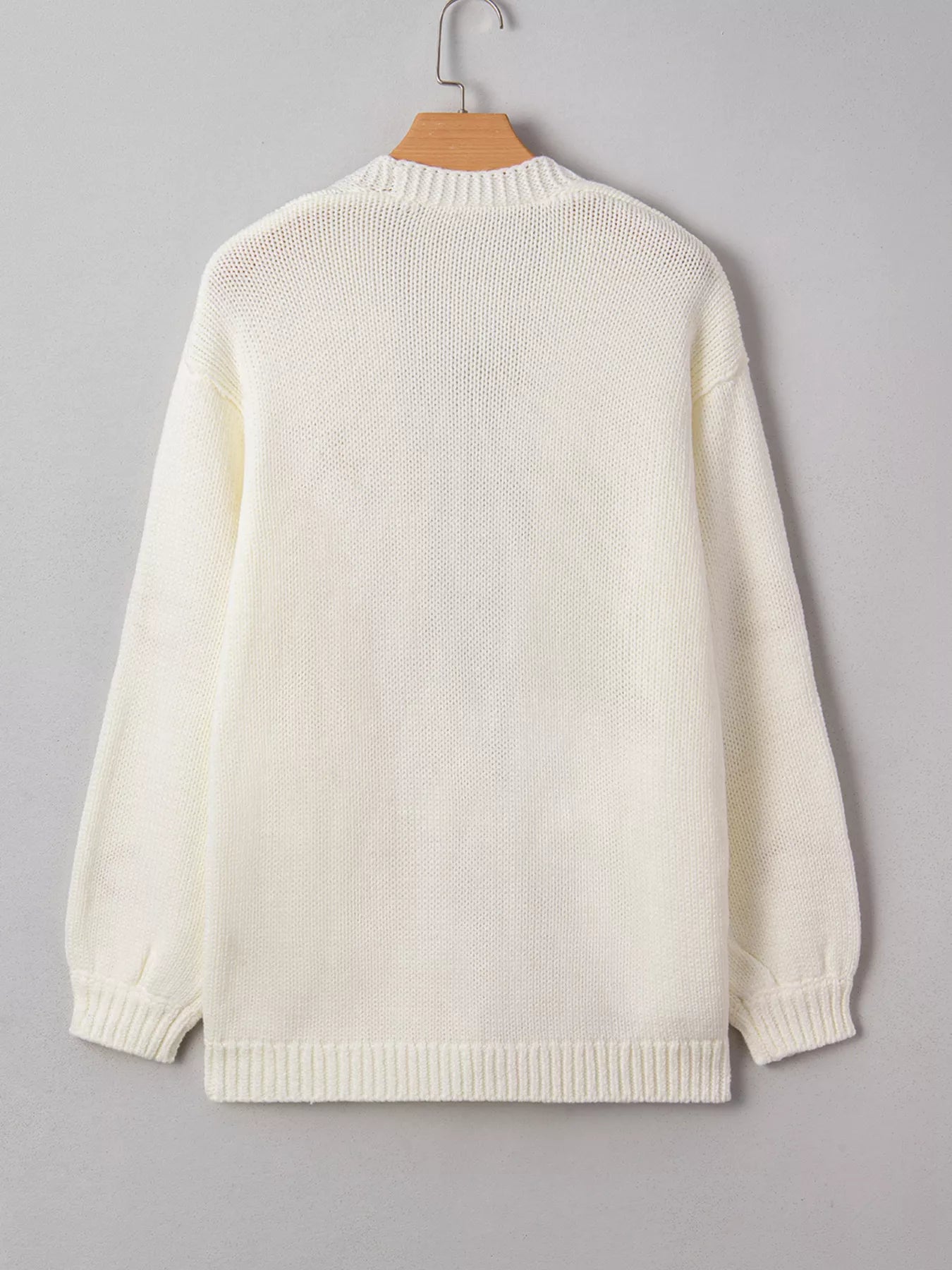 Back view of a cream knit cardigan with ribbed cuffs and hem, hanging on a wooden hanger.