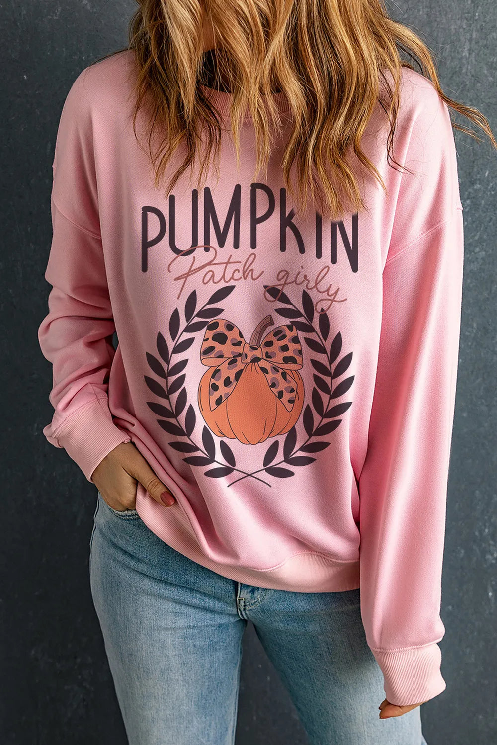 A woman wears a pink "Pumpkin Patch Girly" sweatshirt with a pumpkin graphic.