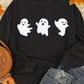 A black long-sleeve sweatshirt with three white ghost figures is displayed with jeans.