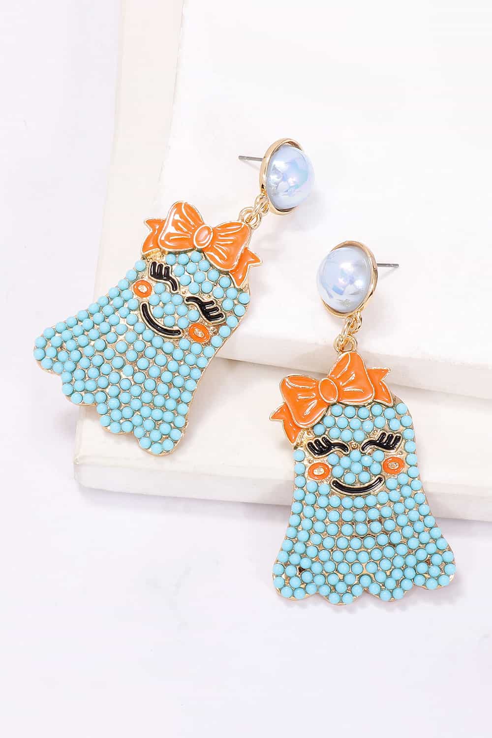 Smiling ghost shape synthetic pearl earrings with an orange bow.
