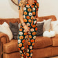 A woman models a pumpkin-printed short-sleeve top and pants lounge set.