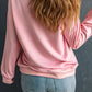 Back view of a woman wearing a pink sweatshirt and blue jeans.