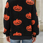A woman from behind wears a black fuzzy sweater with orange pumpkin faces.
