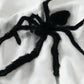 White oversized hoodie with a large black fuzzy spider graphic.