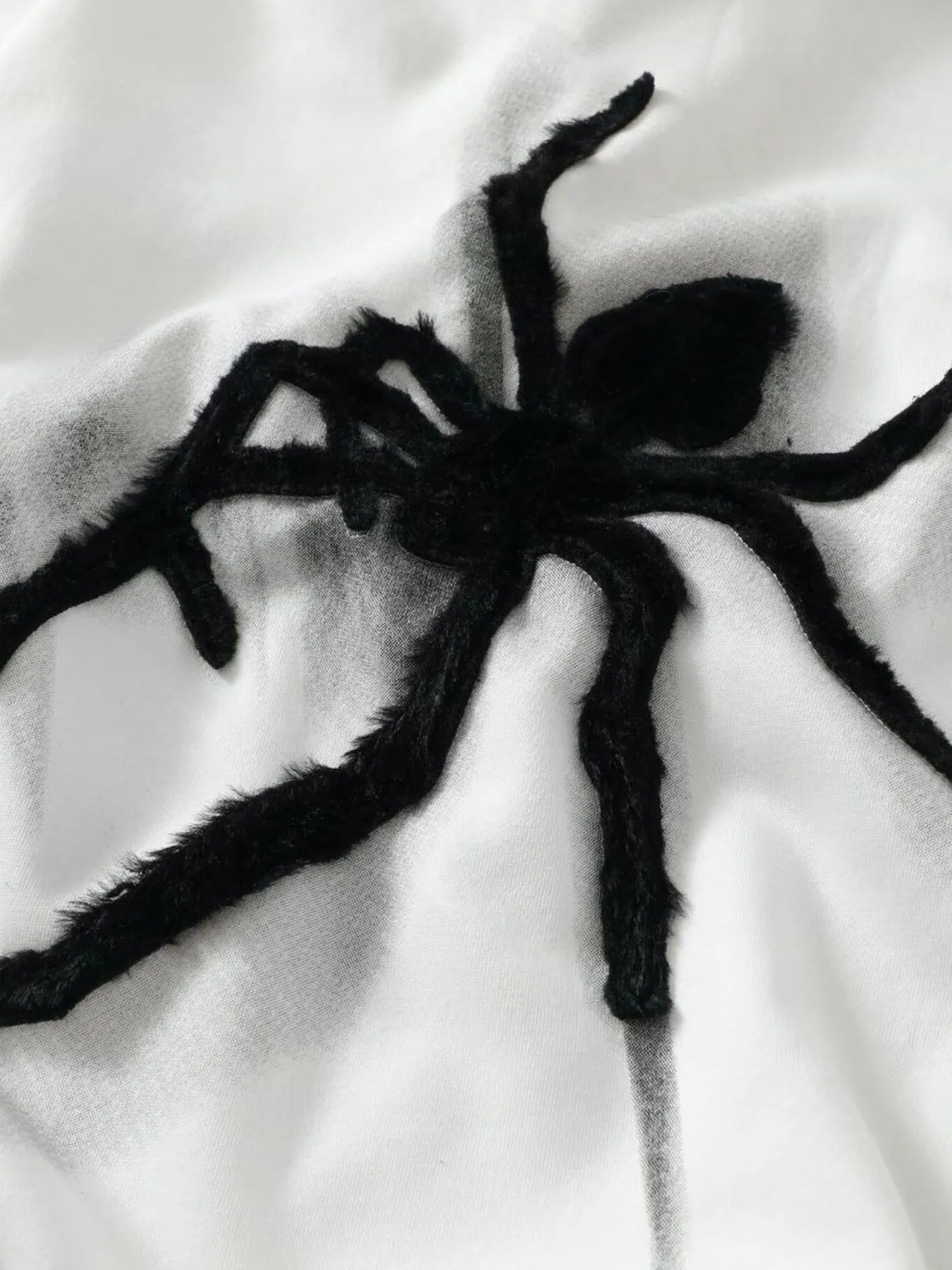 White oversized hoodie with a large black fuzzy spider graphic.