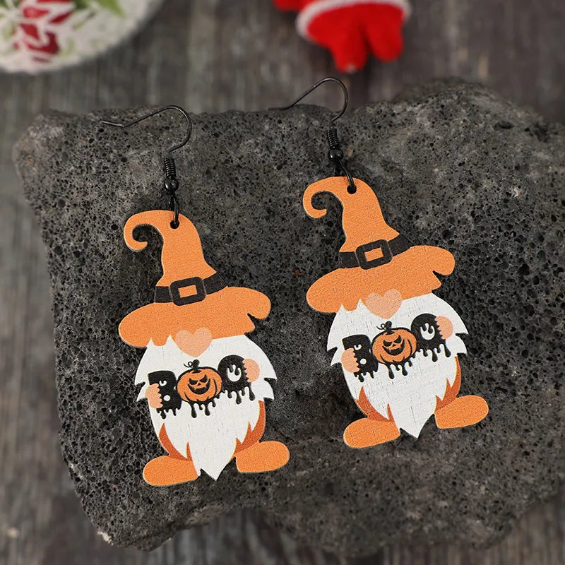 A pair of wooden dwarf earrings with orange hats, white beards, and "BOO" with a pumpkin.