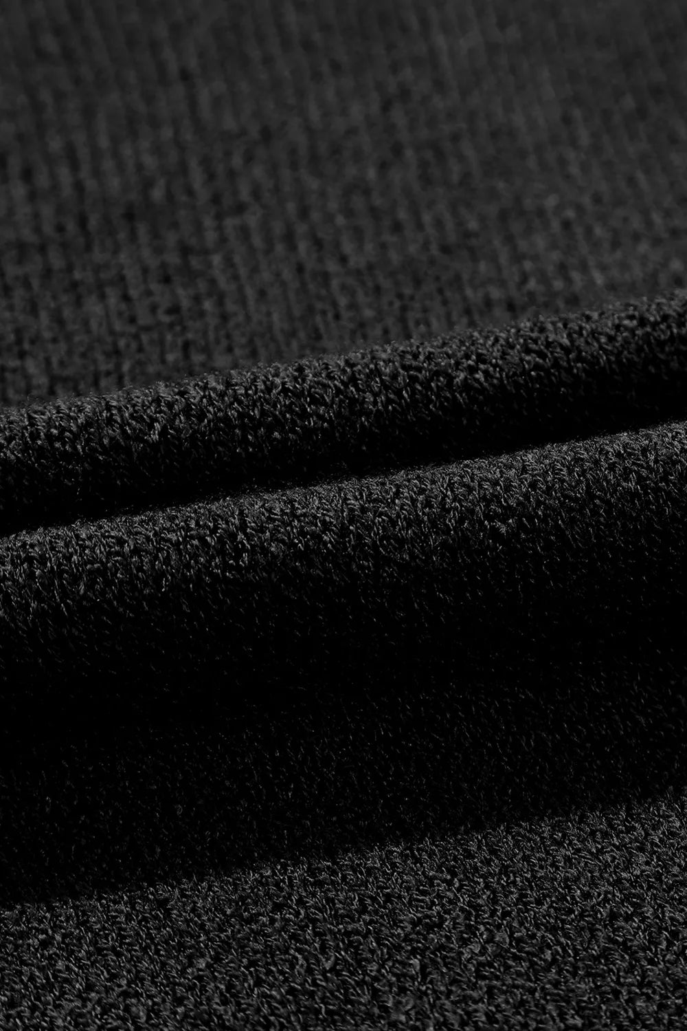 Close-up of black knit fabric with visible texture and folds.