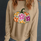 A woman wears a beige drop-shoulder sweatshirt with a colorful floral pumpkin graphic.
