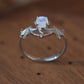 Sterling silver bat ring with a moonstone center on a wooden surface.