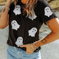 A woman wears a black short-sleeve t-shirt with glitter ghost graphics.