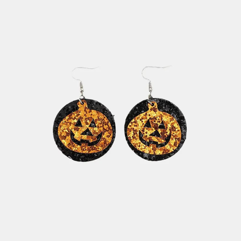 Two glittery black and orange pumpkin-shaped dangle earrings are displayed.