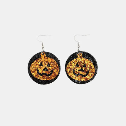 Two glittery black and orange pumpkin-shaped dangle earrings are displayed.