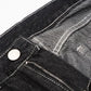 Close-up of black denim jeans with white stitching, a silver button, and a zipper.
