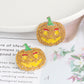 Two rhinestone-encrusted pumpkin earrings with green stems and red eyebrows.