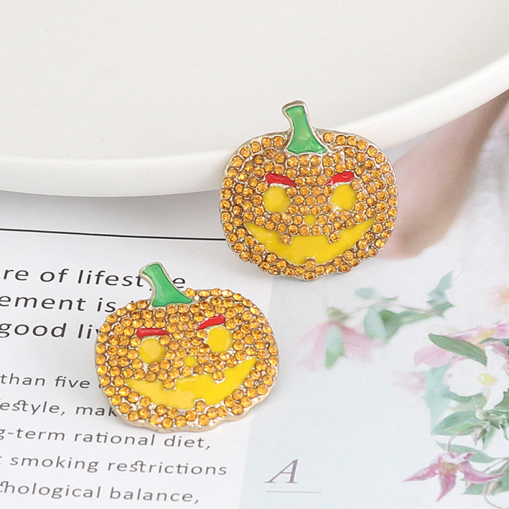 Two rhinestone-encrusted pumpkin earrings with green stems and red eyebrows.