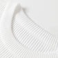 Close-up of a white ribbed knit sweater with a round neck.