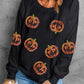 A woman wears a black dropped shoulder sweatshirt with glittery pumpkin designs.