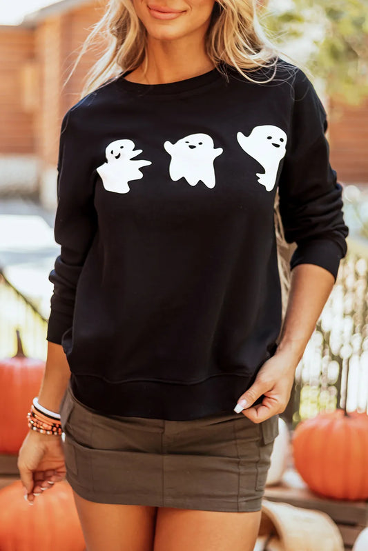 A woman wears a black long-sleeve sweatshirt with three white ghost graphics.