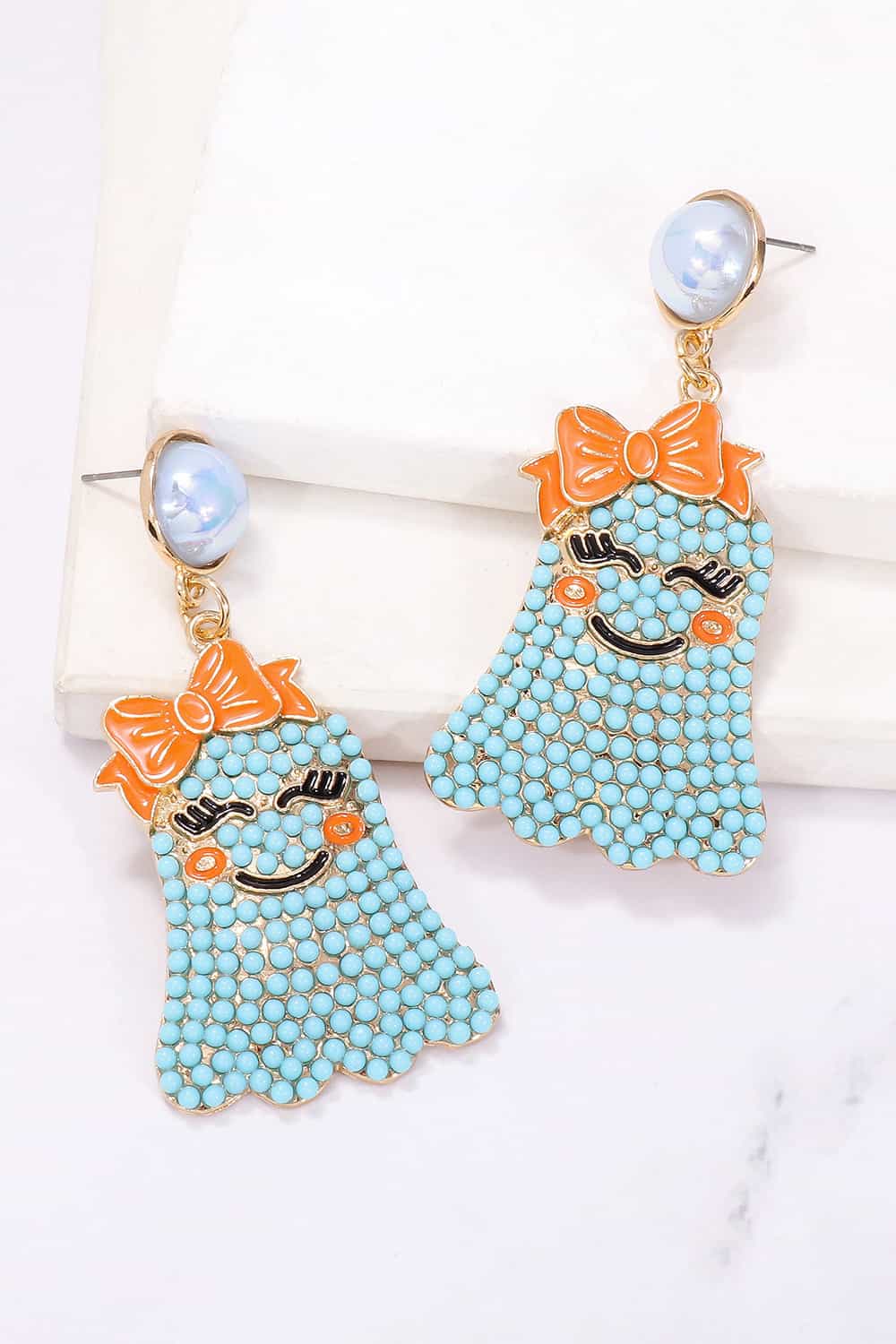 Smiling ghost shape synthetic pearl earrings with orange bows and blue beads.