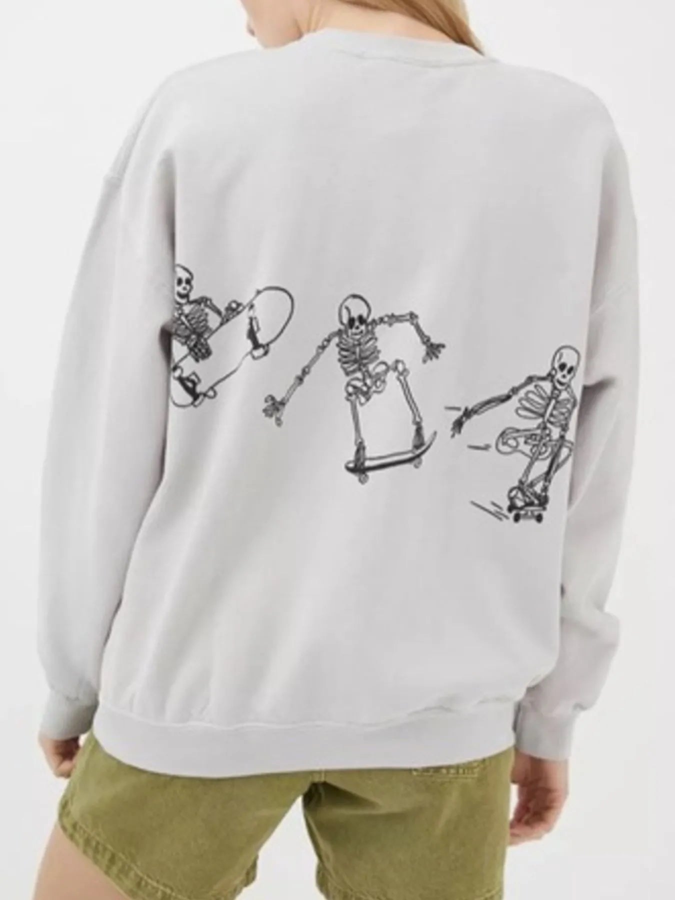 An oversized light grey sweatshirt with a black skeleton graphic skateboarding on the back.