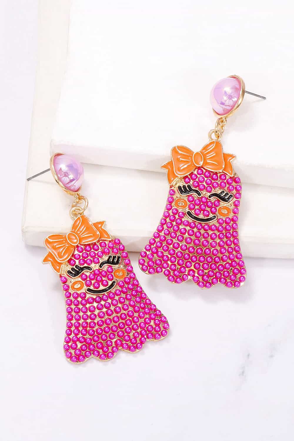 Smiling ghost shape synthetic pearl earrings with an orange bow.