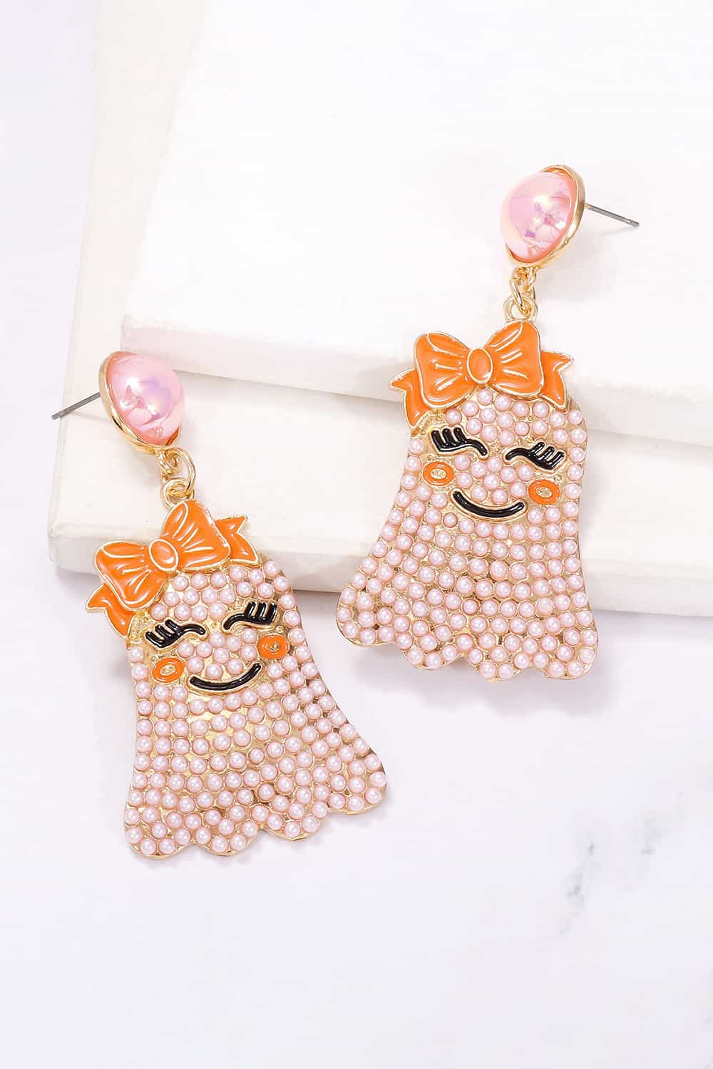 Smiling ghost shape synthetic pearl earrings with orange bows.
