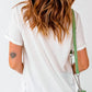 A woman from behind wears a white short-sleeve t-shirt and carries a green purse.