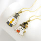 Two Halloween-themed necklaces, one with a lantern and one with a ghost, on a white surface.