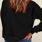A woman from behind wears a black dropped shoulder sweatshirt and blue jeans.
