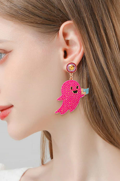 A woman wears a pink ghost-shaped dangle earring with a synthetic pearl stud.