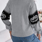 Gray long-sleeve sweater with black pumpkin designs on the sleeves.