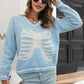 A woman wears a light blue skeleton pattern v-neck long sleeve pullover sweater.